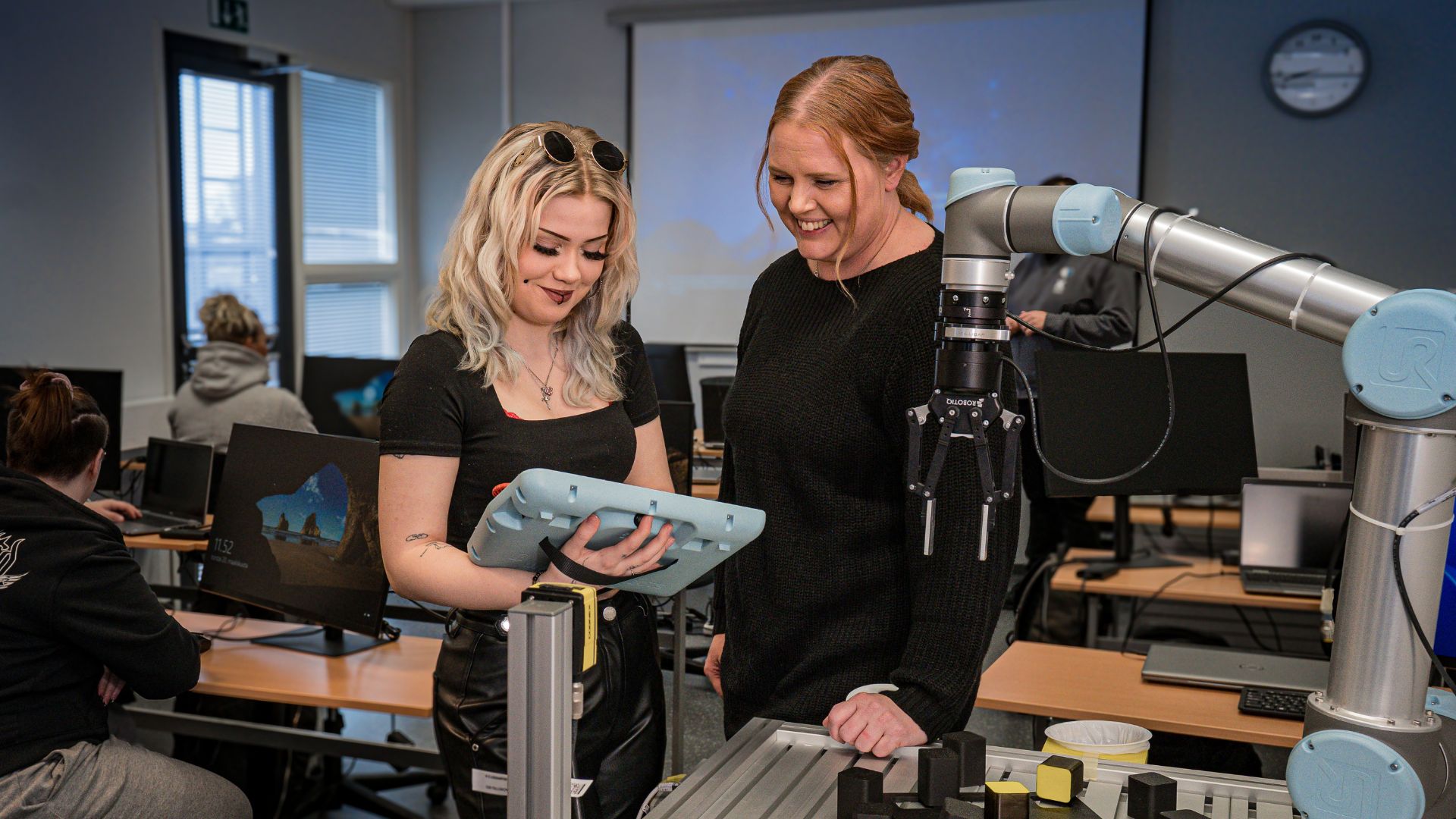 Students exploring a robot in a classroom.